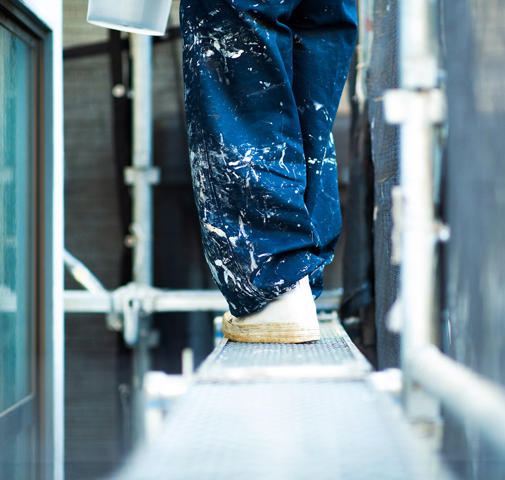 足場から外壁塗装をしている職人